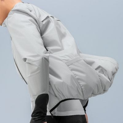 Light gray lightweight windbreaker jacket on person pulling the hood up for outdoor activity, close-up of clothing details, men's sportswear, casual fashion, urban style breathable fabric.