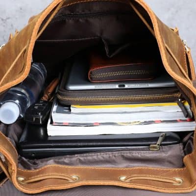 Organized leather bag with laptop, notebooks, water bottle, and accessories, ideal for professional and travel use.