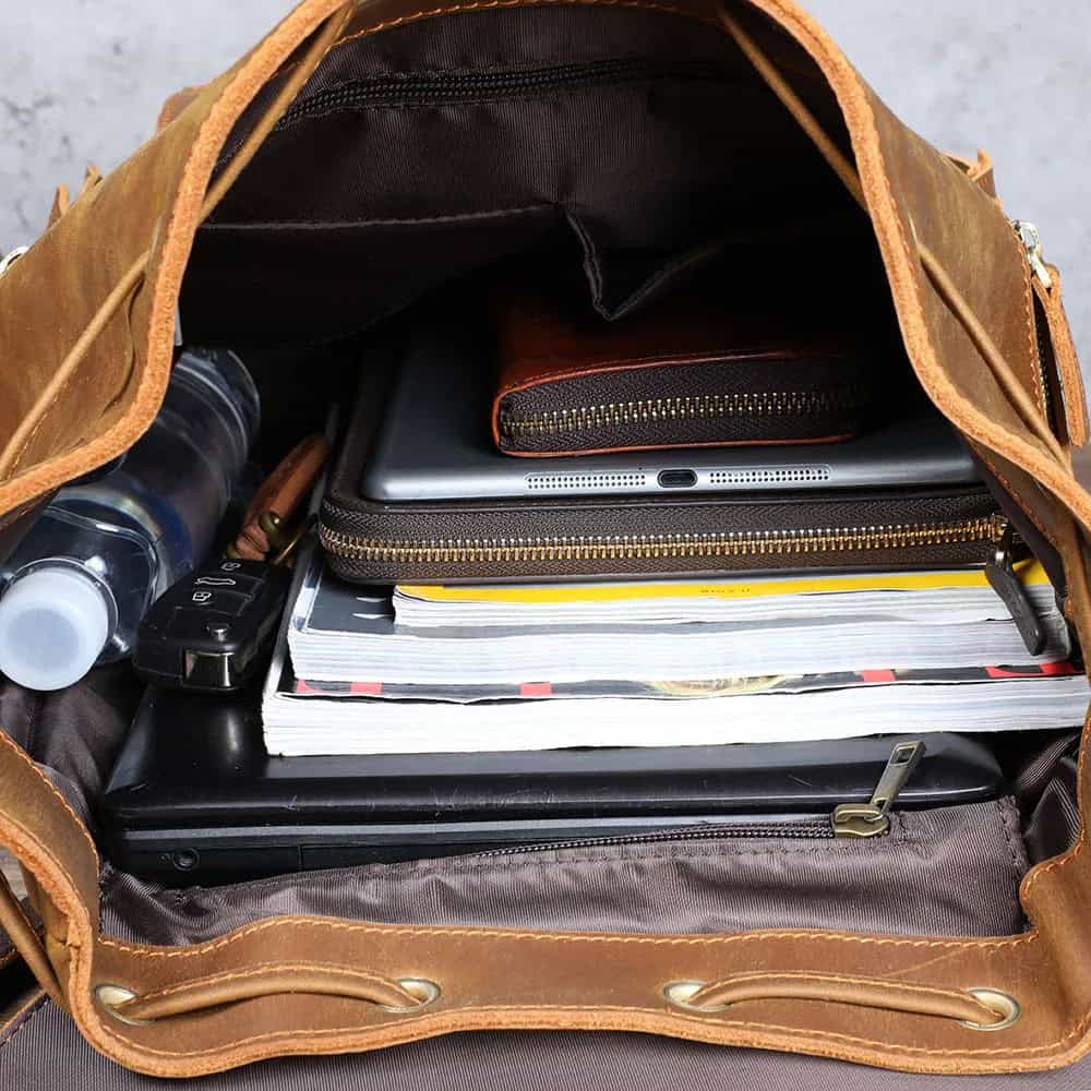 Organized leather bag with laptop, notebooks, water bottle, and accessories, ideal for professional and travel use.