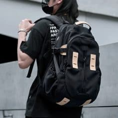 Backpack with multiple compartments and beige accents standing on a person wearing a black face mask and T-shirt at Monalisa Medical store.