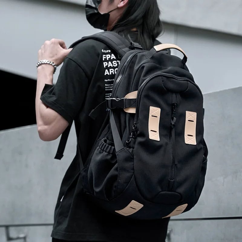 Backpack with multiple compartments and beige accents standing on a person wearing a black face mask and T-shirt at Monalisa Medical store.