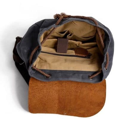 Spacious black and brown canvas tote bag with tan interior, multiple compartments, and leather accents, perfect for travel, work, or daily use.