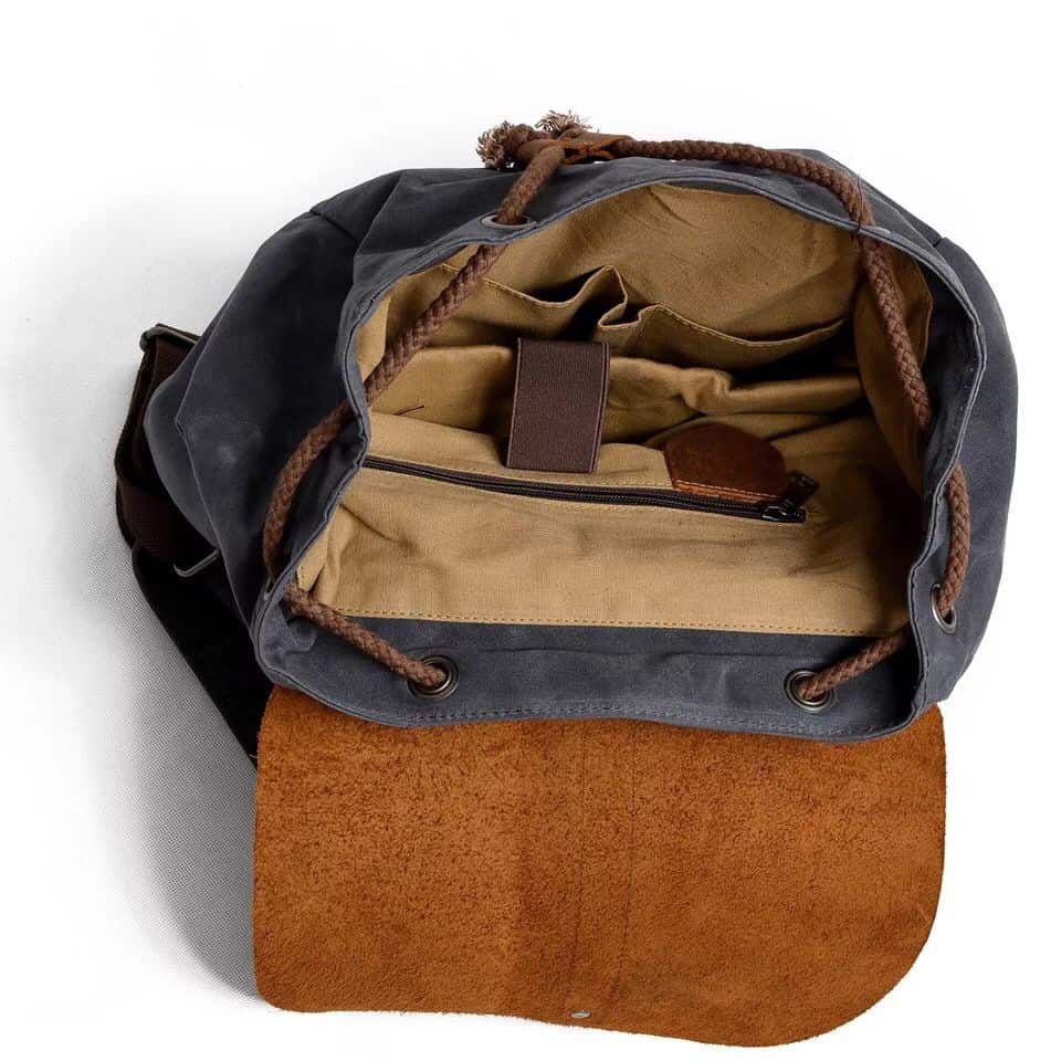 Spacious black and brown canvas tote bag with tan interior, multiple compartments, and leather accents, perfect for travel, work, or daily use.