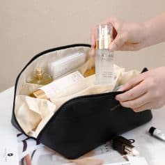Hyaluronic acid skincare serum inside black cosmetic bag with various beauty products and tools for skincare routine.