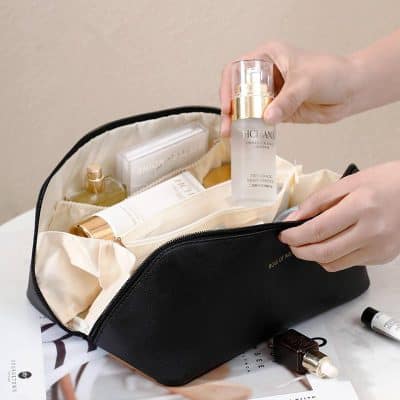 Hyaluronic acid skincare serum inside black cosmetic bag with various beauty products and tools for skincare routine.