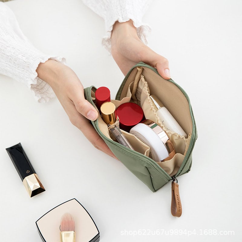 Small green cosmetic bag with skincare and makeup products including lipstick, moisturizer, and foundation.