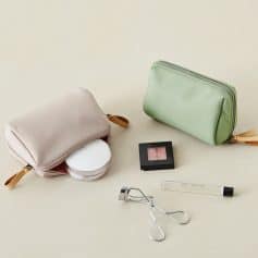 Soft pink and mint green cosmetic pouches with makeup tools and accessories for eye care and beauty grooming.