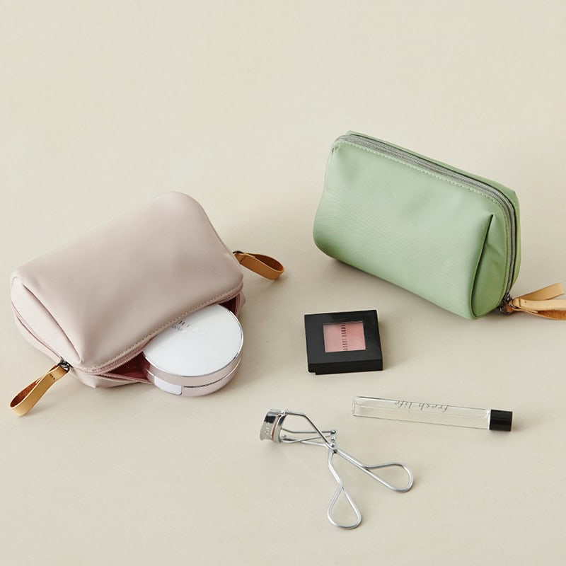 Soft pink and mint green cosmetic pouches with makeup tools and accessories for eye care and beauty grooming.