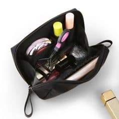 Shabby and used black cosmetic bag with makeup brushes, lipstick, blush, and beauty tools organized inside.
