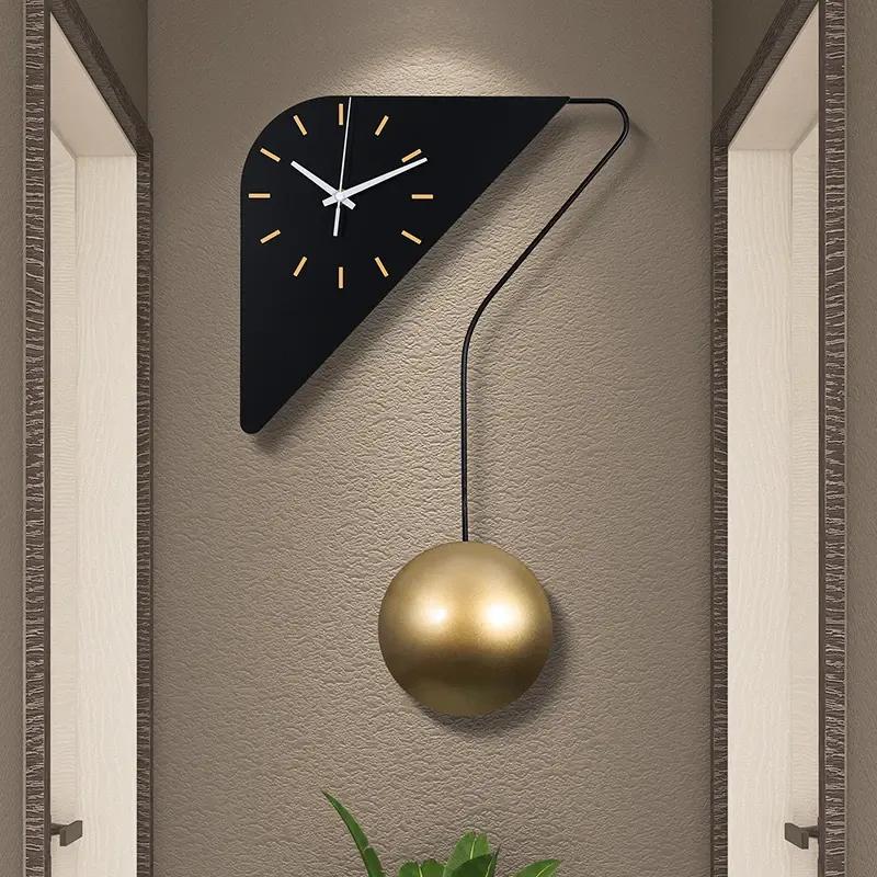 Contemporary modern wall clock with a sleek black triangular design and gold pendulum, perfect for stylish home or office decor.