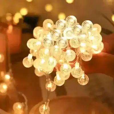 String of decorative warm white LED string lights on transparent spherical bulbs for cozy ambient lighting. Perfect for home decor, parties, and outdoor spaces.