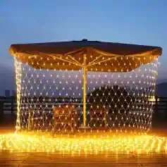 Illuminated outdoor umbrella with decorative string lights at dusk, perfect for outdoor decor and gatherings.