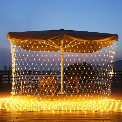 Illuminated outdoor umbrella with decorative string lights at dusk, perfect for outdoor decor and gatherings.