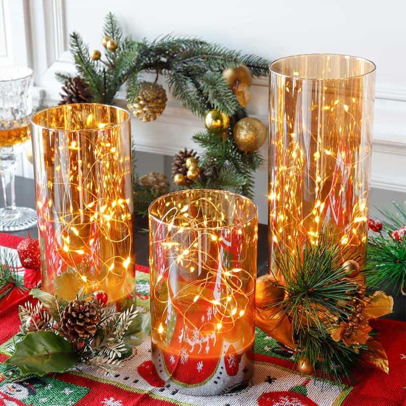 Golden candle holders with LED string lights for festive holiday decor at Monalisa Store. Elegant Christmas centerpiece with pinecones, ornaments, and greenery. Perfect for creating a warm, cozy atmosphere.