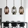 Vintage-style oil lantern pendant lights hanging over a modern dining table in a stylish interior, adding rustic charm and warm lighting to the Monalisa Store.