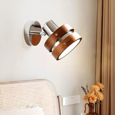 Modern wall-mounted LED light fixture with wood and chrome accents, illuminating contemporary bedroom decor.