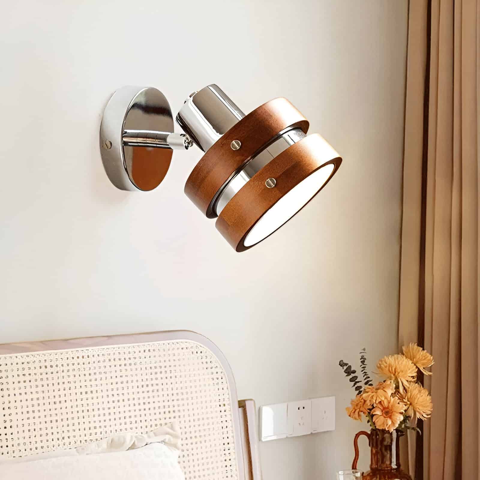 Modern wall-mounted LED light fixture with wood and chrome accents, illuminating contemporary bedroom decor.