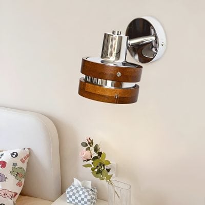 Modern wall-mounted lamp with wood and chrome finishes in a stylish bedroom setting.