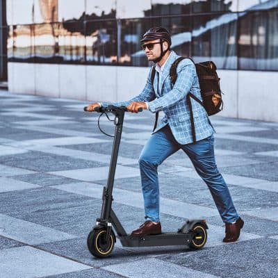 Electric scooter for commuting with stylish rider in business attire on urban sidewalk, modern transportation, eco-friendly city travel, Monalisa Store opt, stylish, urban transportation, eco-friendly, city commute.