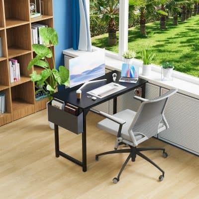 Modern home office setup with a sleek black desk, ergonomic chair, large monitor, and indoor plants, overlooking a lush outdoor garden via large window; perfect for productivity and aesthetics.