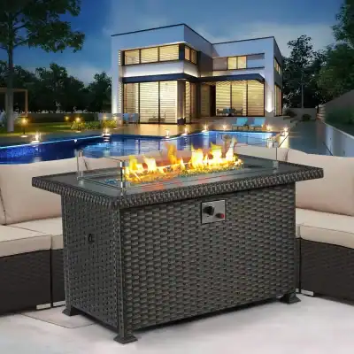Modern outdoor fire pit with glass enclosure and wicker base, perfect for patio lounging, with a contemporary home and pool area in the background.