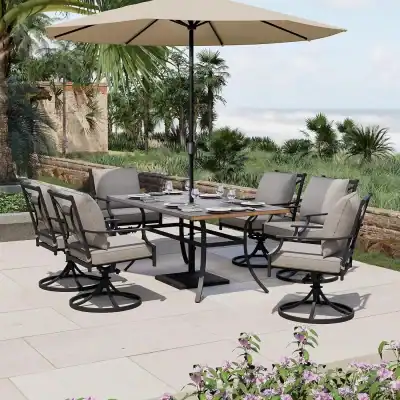 Elegant outdoor dining set with cushioned chairs, a wooden table, and a large umbrella, surrounded by lush tropical landscaping—ideal for a relaxing meal or gathering in a scenic environment.
