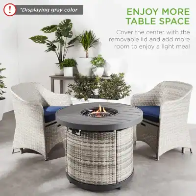 Stylish outdoor fire pit table with gray wicker base and round black top, paired with comfortable wicker armchairs, perfect for creating a cozy patio space.