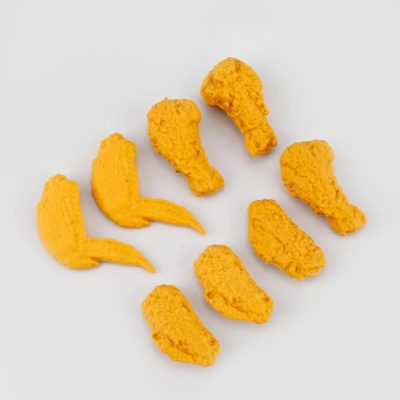 Bright yellow 3D-printed chicken drumsticks and wings, showcasing custom design accessories for opt and medical purposes, displayed on a white background.