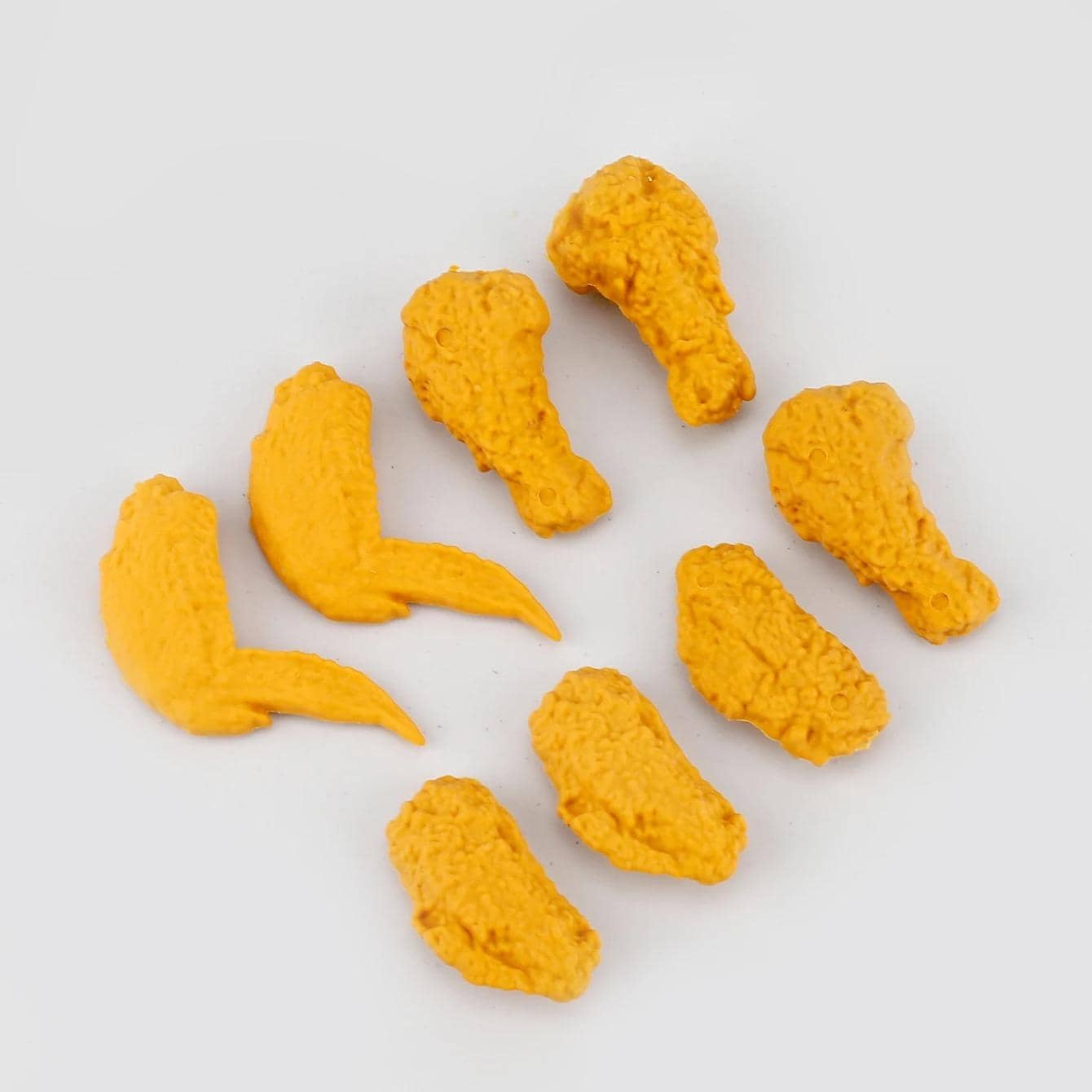 Bright yellow 3D-printed chicken drumsticks and wings, showcasing custom design accessories for opt and medical purposes, displayed on a white background.