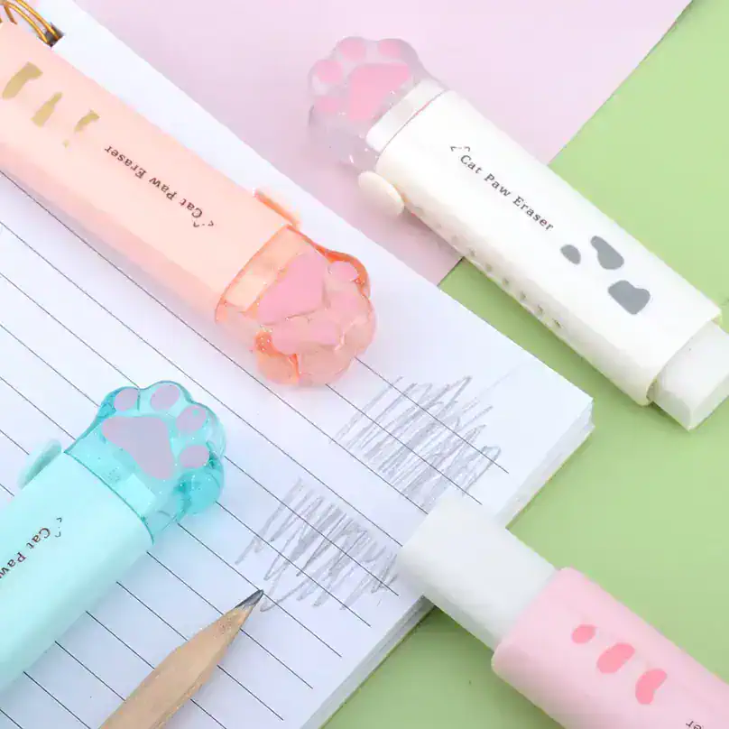 Colorful cat paw erasers and pens on a notebook, perfect for students and pet lovers, available at Monalisa Store for cute stationery accessories.