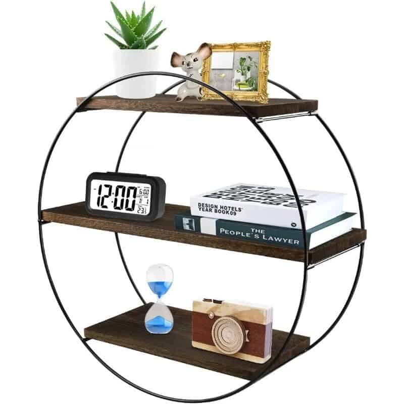 A stylish round wall shelf displaying a digital clock, decorative camera, books, an hourglass, and figurines, ideal for home decor, office organization, and modern interior design.
