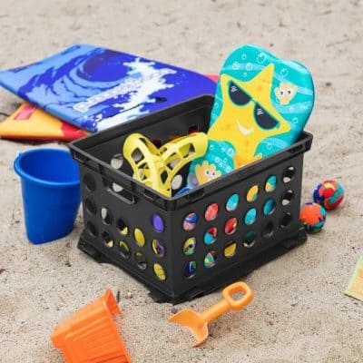 Bright beach toy storage basket filled with beach tools, sand molds, and floaties, perfect for kids' beach day fun and organization. Ideal for outdoor play and beach trips for children.