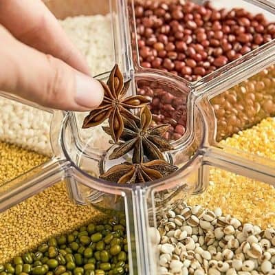 Vibrant assortment of spices in clear storage jars, including star anise, beans, seeds, and herbs, ideal for culinary uses and kitchen organization.