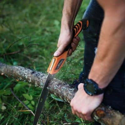 A person using an ergonomic pruning saw to cut a tree branch outdoors, showcasing safe gardening and tree trimming tools for yard maintenance.