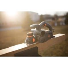 Cordless electric planer on wooden beam, ideal for woodworking, carpentry, and renovation projects, featuring durable design and easy handling for smooth finishing.