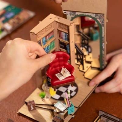 Detailed miniature library diorama featuring a red armchair, tiny bookshelves, and staircase, perfect for desk decor or as a collectible piece. Ideal for book lovers and miniature enthusiasts.