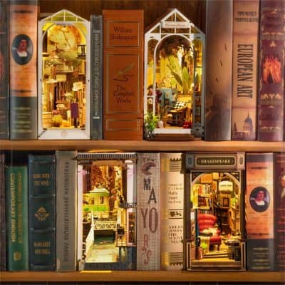 A miniature dollhouse display set against vintage books, featuring detailed room scenes including cozy furniture and decorative elements, ideal for vintage book and dollhouse collectors.