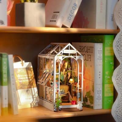 Detailed miniature greenhouse with vibrant flowers, cozy furniture, and warm lighting, perfect for garden enthusiasts and interior decor lovers.