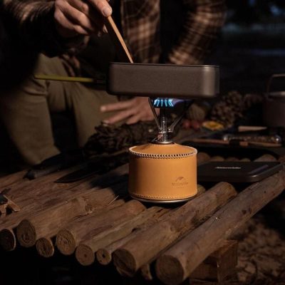 Stainless steel camping stove with leather base for outdoor cooking, perfect for camping, hiking, and off-grid adventures. Compact and portable design for easy transport and outdoor use.