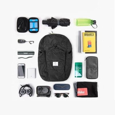 Compact travel bag with vital accessories including sunglasses, protective cases, water bottle, chargers, and other travel gear for eyewear and optometry related needs.