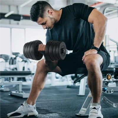 Male lifting heavy dumbbells at gym for muscle building, fitness, and health improvement.