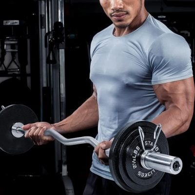A muscular man in a blue athletic shirt lifting a dumbbell at Monalisa Medical store to promote fitness and eye health.