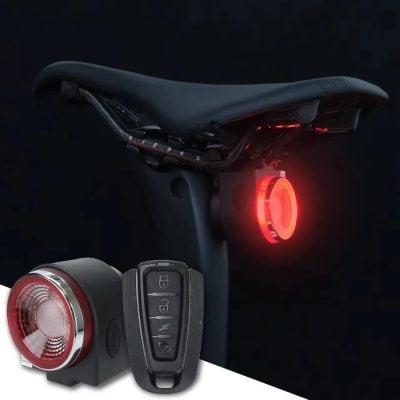 Close-up of a bicycle seat with an integrated red LED safety light and a remote control device for adjusting brightness and flashing modes, designed for cyclist safety.