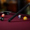 Pool cue with billiard balls on a red table for optimal gameplay.