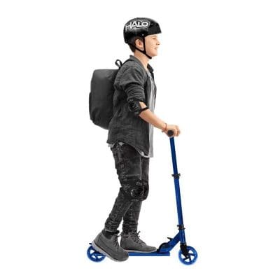 Child with helmet riding a scooter, wearing knee and elbow pads, backpack, and casual outfit, white background.