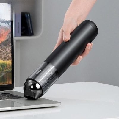 A sleek black electric pepper mill being used over a laptop, perfect for fresh seasoning during cooking or dining, designed for modern kitchens and convenience.