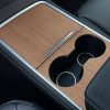 Close-up view of a car's wooden center console with cup holder and storage compartment, emphasizing luxury and comfort features for drivers and passengers.
