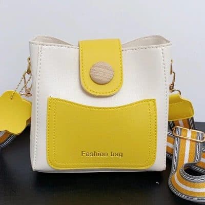 Bright yellow and white fashion handbag with adjustable striped strap, front pocket, and wooden button closure, perfect for stylish accessories.