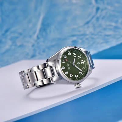 Elegant stainless steel men's watch on white surface with blue background, perfect for fashion and everyday use.