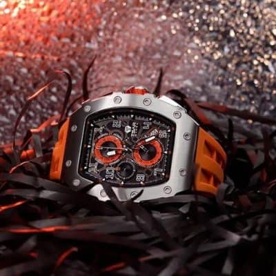 A high-end sports watch with a bold design, black dial, and orange accents, showcased on a bed of black shredded paper for a stylish, modern look. Perfect for luxury watch enthusiasts and collectors.